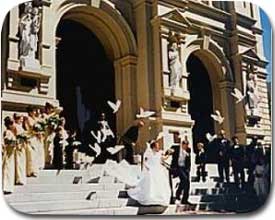 bride and groom decend stairs at church while a flock of doves flies into the air